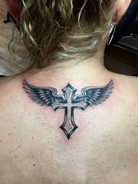 Tattoo cross and wings - A design that stands out among the beautiful cross tattoos, giving a much more divine appeal, this cross encompasses the Holy Trinity- the Father, Son and Spirit, altogether in a cross to carry with entwined thorns stinging and embracing the neck. Cross and Feathered Wings Tattoo Design 